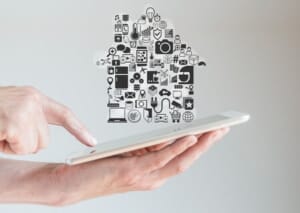 Dem Smart Home gehört die Zukunkft. Zu sehen ist ein Tablet, auf dem sich Steurungssymbole befinden, die die Form eines Hauses bilden.
